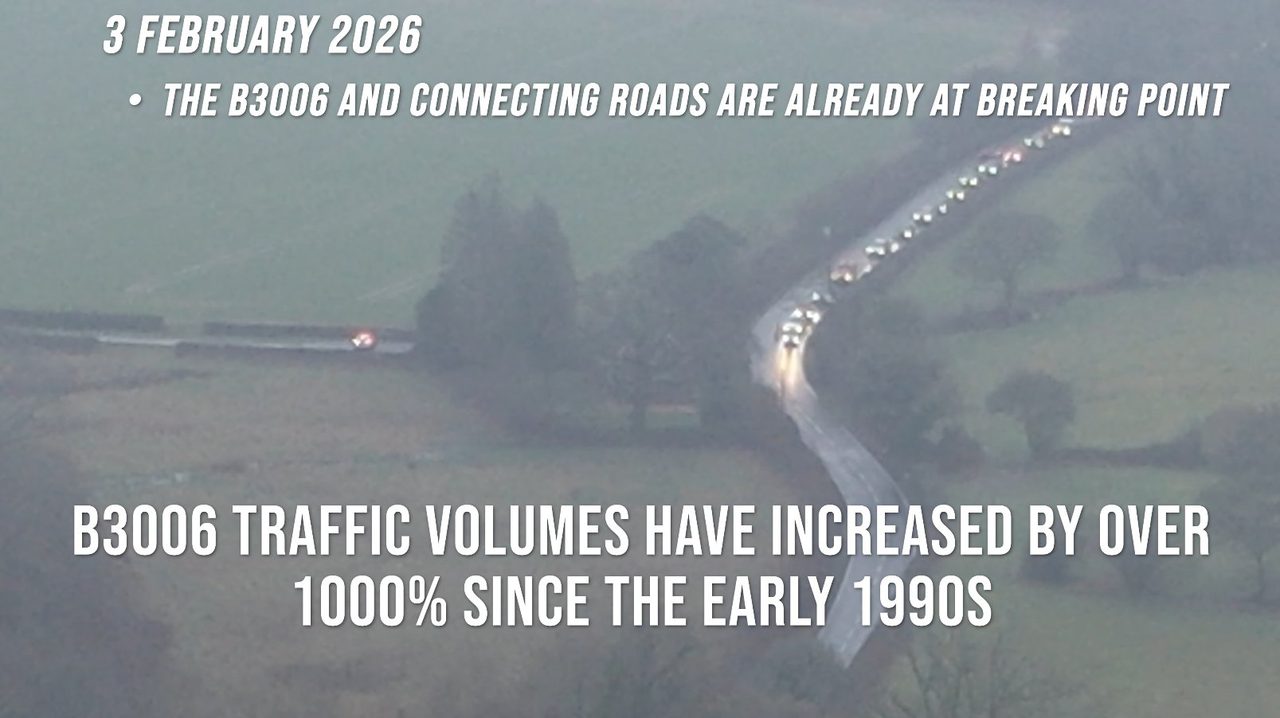 Foggy aerial of the B3006 on 3 February 2026: a long line of cars nose-to-tail along the rural road at peak time.