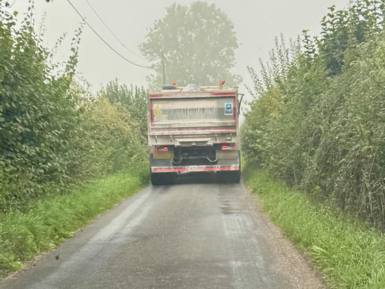 A tipper lorry on Mill Lane between Empshott Grange and the B3006, filling the lane from verge to verge between high hedges.