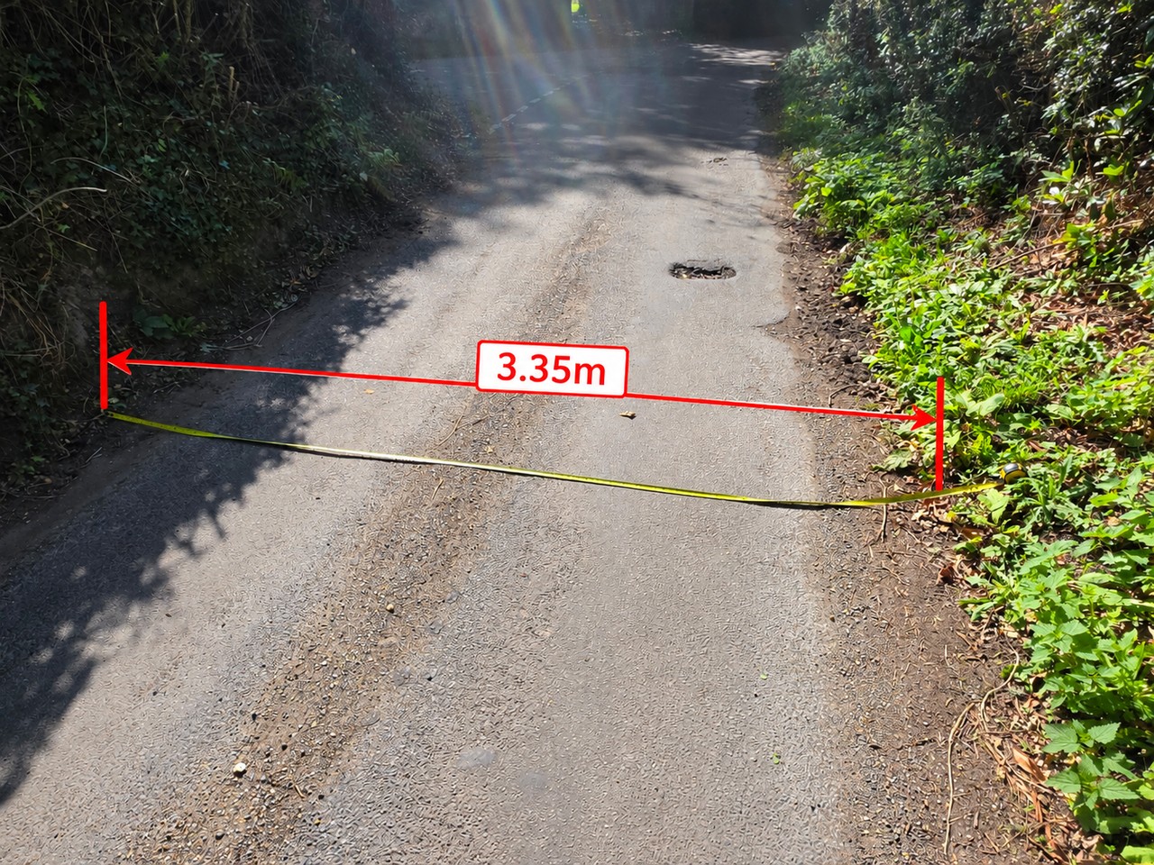 A tape measure across Mill Lane recording a carriageway width of approximately 3.35 m at the swept-path location.